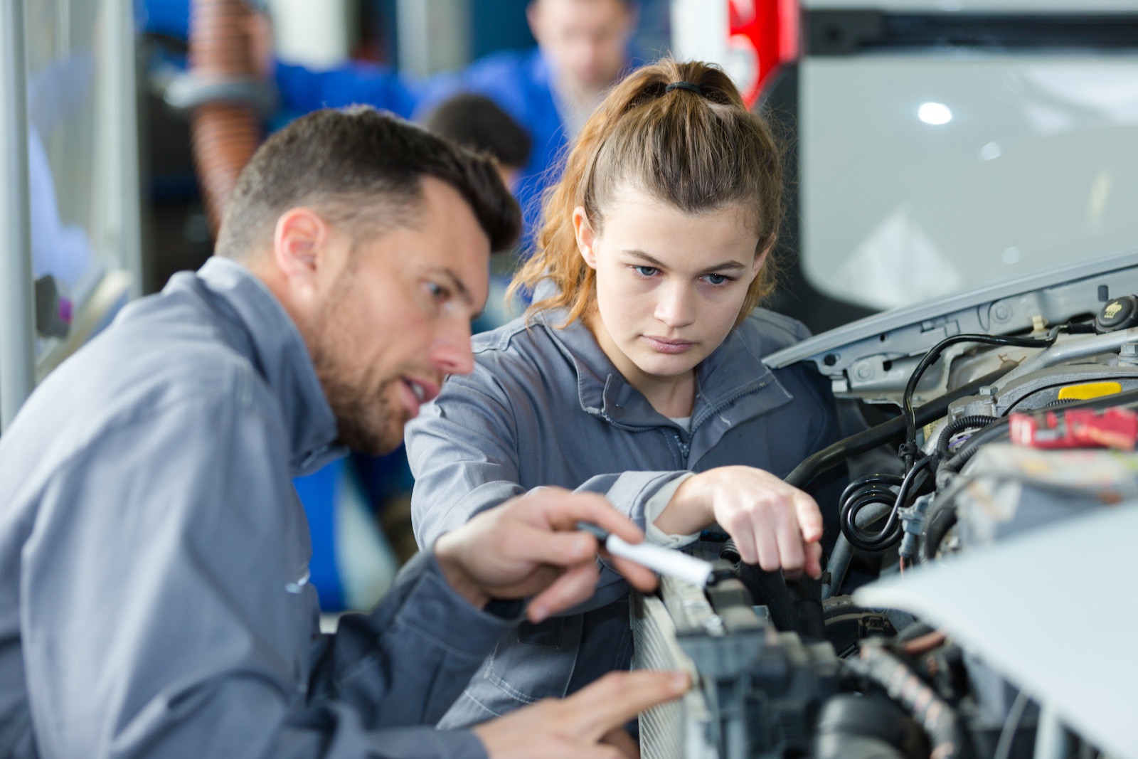woman as a mechanic apprentice in auto repair shop woman as a mechanic apprentice in auto repair shop